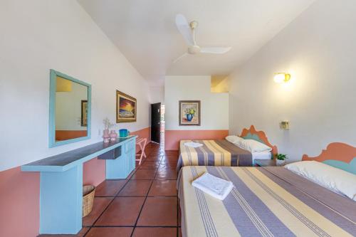 a hotel room with two beds and a desk at Hotel Flor de Maria in Puerto Escondido