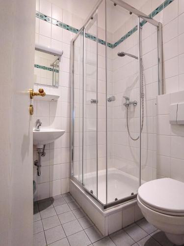a bathroom with a shower and a toilet and a sink at Domhotel in Sankt Wendel