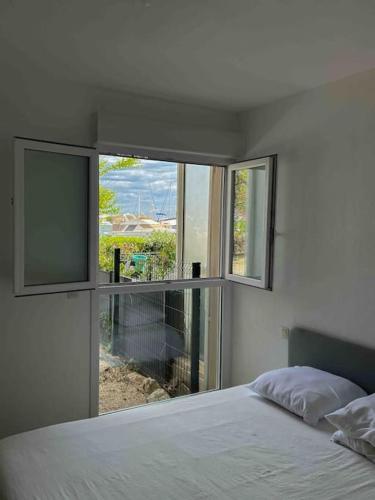 une chambre avec un lit et une grande fenêtre dans l'établissement Face au bateaux, Neuf, 2 chambres , jardin, à Canet