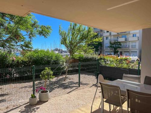 a patio with a table and chairs and a fence at Face au bateaux, Neuf, 2 chambres , jardin in Canet-en-Roussillon