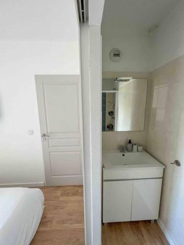 - une salle de bains blanche pourvue d'un lavabo et d'un lit dans l'établissement Face au bateaux, Neuf, 2 chambres , jardin, à Canet