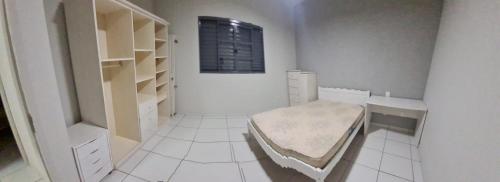 uma casa de banho branca com uma cama num quarto em Casa Perto da Expovale em Ivaiporã