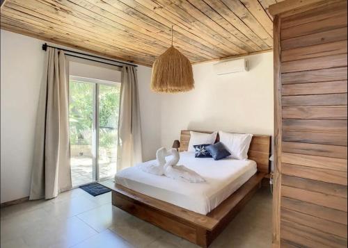 a bedroom with a white bed with a wooden ceiling at Villa with pool and tropical garden Madagascar in Marokindro