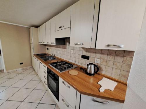 a kitchen with white cabinets and a wooden counter top at Maison Chez Bollon in Aosta