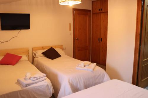 Pokój z dwoma łóżkami i telewizorem na ścianie w obiekcie El Refugio Valdelinares Gastro Hostal w mieście Valdelinares