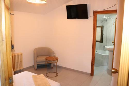 ein Bad mit einem Stuhl und einem TV an der Wand in der Unterkunft El Refugio Valdelinares Gastro Hostal in Valdelinares