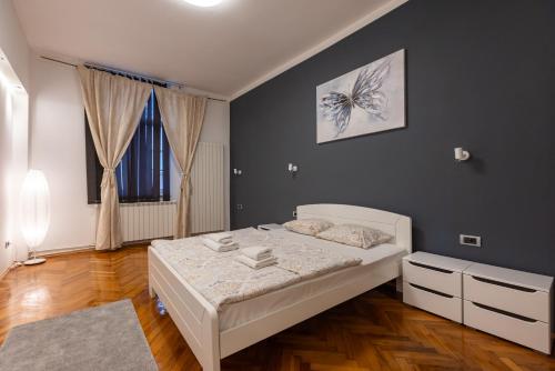 a bedroom with a white bed and a large window at Central Park Apartments in Belgrade