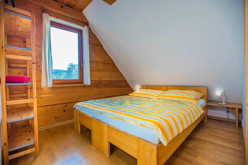 a bed in a wooden room with a window at Holiday Raj in Bešeňová