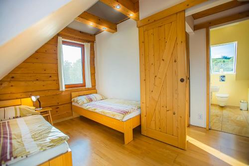 a bedroom with a bed and a wooden wall at Holiday Raj in Bešeňová