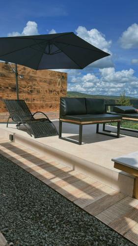 un banc, un canapé et un parasol dans l'établissement Canrobert Village, à Pedro II