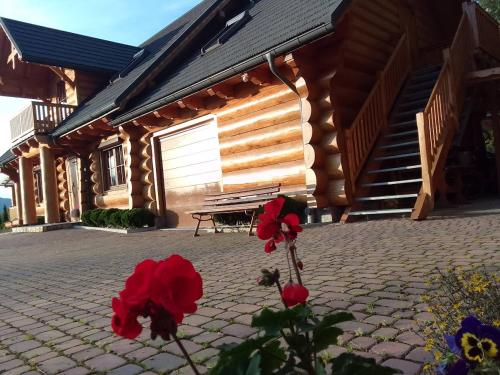 un banc devant une cabine avec des fleurs rouges dans l'établissement U Janusza i Grażyny, à Ściegny