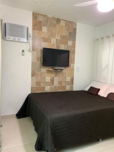 a bedroom with a bed and a tv on a wall at Casa em Arraial do Cabo na praia grande in Arraial do Cabo
