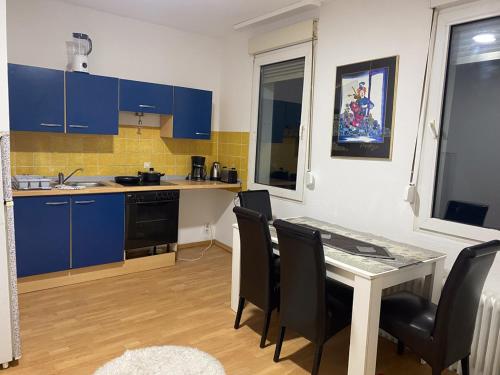 cocina con armarios azules, mesa y sillas en Shared Serenity accommodation, en Wuppertal
