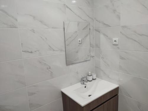 a white bathroom with a sink and a mirror at Penedo Grande suítes Estúdio in São Bartolomeu de Messines