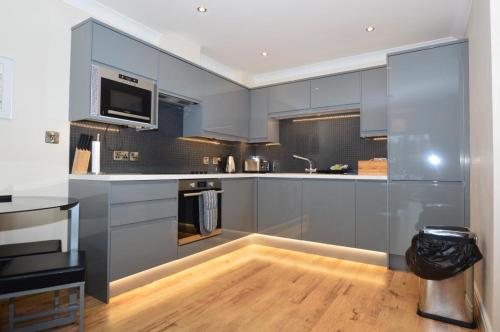 a large kitchen with blue cabinets and a wooden floor at Swanning Off Whitby with Parking in Whitby