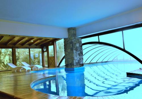 a swimming pool in a house with a glass wall at Hosteria Patagon in Villa La Angostura