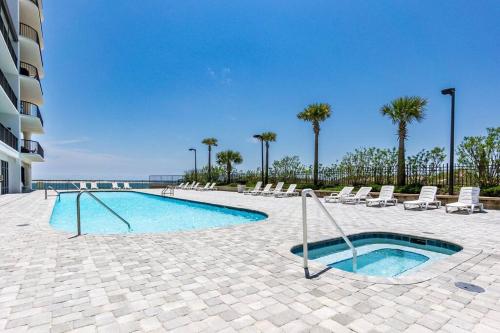 a swimming pool with lounge chairs and a swimming pool at Grand Pointe Unit 506 in Orange Beach