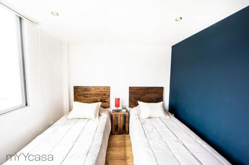 Duas camas num quarto com uma parede azul em Sophisticated Park Venue Apartment Near Polanco - Nadal 101 em Cidade do México