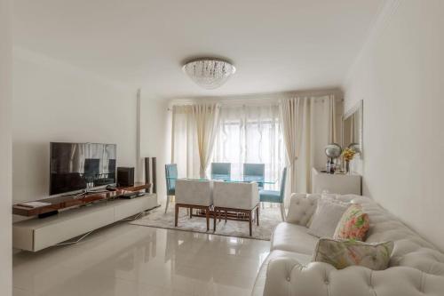 a white living room with a couch and a tv at Maison Soleil Oeiras in Oeiras