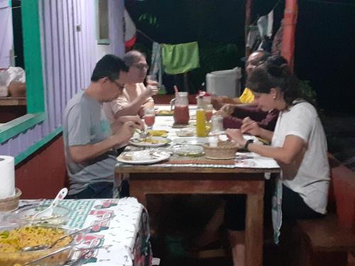 un grupo de personas sentadas alrededor de una mesa comiendo comida en POUSADA CANTO DOS PASSÁROS, en Manaus