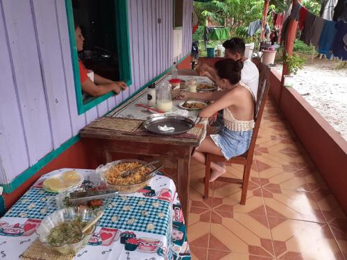 馬瑙斯的住宿－POUSADA CANTO DOS PASSÁROS，坐在餐桌旁吃食物的男人和女人