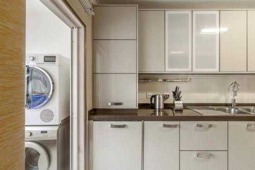 a kitchen with white cabinets and a washer and dryer at Maison Soleil Oeiras in Oeiras