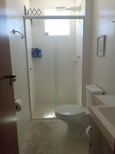 a white bathroom with a shower and a toilet at Praia de Palmas in Governador Celso Ramos