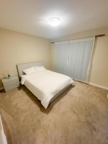 a bedroom with a white bed and a window at Entire house to yourselves - NO basement sharing in Regina
