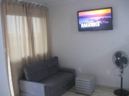 a living room with a couch and a television on the wall at Cabana econômica com 2 quartos in Machadinho