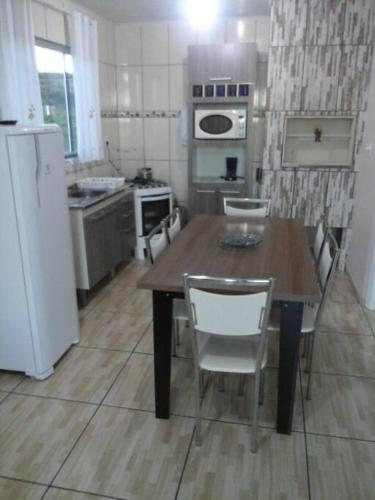 a kitchen with a wooden table and a white refrigerator at Cabana econômica com 2 quartos in Machadinho