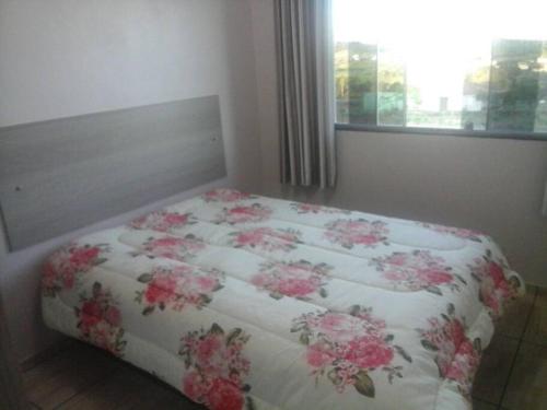 a bed with a blanket with pink flowers on it at Cabana econômica com 2 quartos in Machadinho