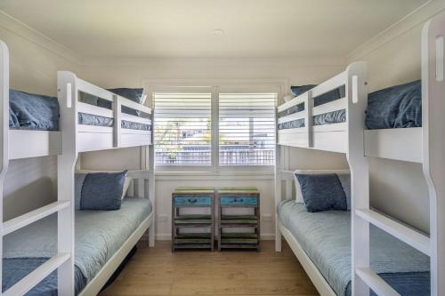 two bunk beds in a room with a window at Eurie Eurie on Beachview in Berrara