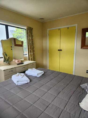 1 dormitorio con 1 cama con espejo y toallas en Harakeke Homestay, en Hastings