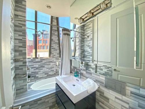 La salle de bains est pourvue d'un lavabo et d'une baignoire avec fenêtre. dans l'établissement Gorgeous Three Bedroom West Village Townhouse, à New York