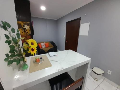 una habitación con una mesa con un jarrón con un girasol en Flat Palladium, en São Vicente