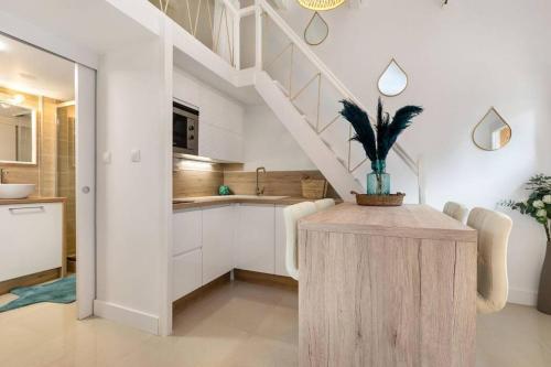 d'une cuisine avec des placards blancs et une table avec une plante. dans l'établissement Appartement Pinède proche Village Naturiste, au Cap d'Agde