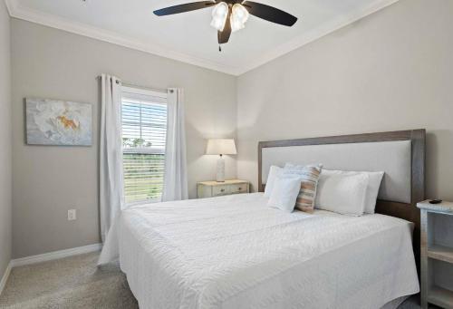 a bedroom with a white bed with a ceiling fan at Paradise Key at Lost Key Golf & Beach Club in Pensacola
