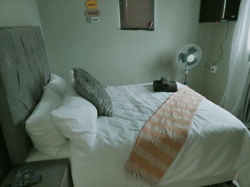 Una cama blanca con almohadas y una manta. en Gentle Breeze, en Burgersfort