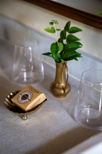 a table with two glasses and a vase with a plant at Na Praça Hotel in Trancoso