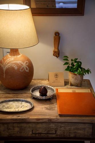 a table with a lamp and a plate and a plant at Na Praça Hotel in Trancoso