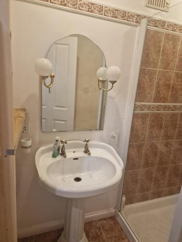 uma casa de banho com um lavatório, um espelho e uma banheira em 51 Nonsuch Walk, Cheam em Cheam