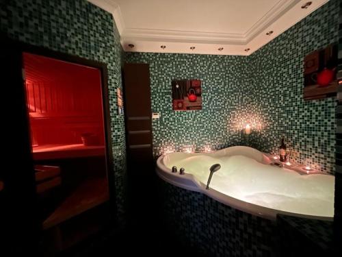 a bathroom with a tub in a green tiled wall at Apartament z małym spa in Gdynia