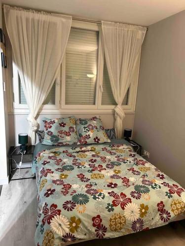 Un dormitorio con una cama con edredón floral y una ventana. en Proche PARIS, Aéroport ORLY, charmant 2 pièces, en Orly