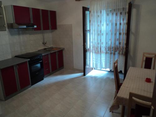a kitchen with red cabinets and a table and a door at Apartments Lička 25 in Split