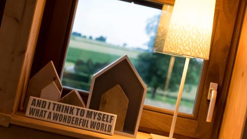 a small wooden house in a window next to a lamp at StroEnzo - RUIME LOFT - 5P - 2SLPK - DAKTERRAS - LAADPAAL - 10MIN Maastricht in Riemst