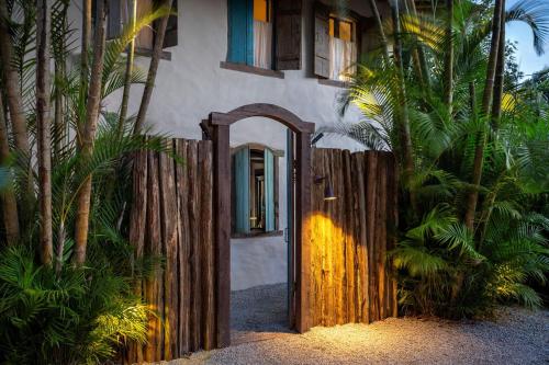 a wooden gate leading to a house with a fence at Na Praça Hotel in Trancoso