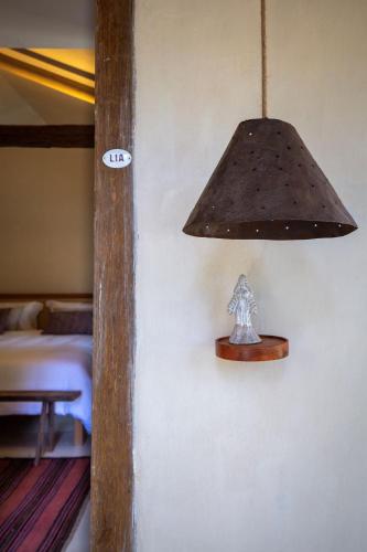 a lamp hanging on a wall next to a bed at Na Praça Hotel in Trancoso