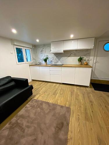 a living room with a black couch and a kitchen at Appartement neuf paisible proche aéroport in Morangis