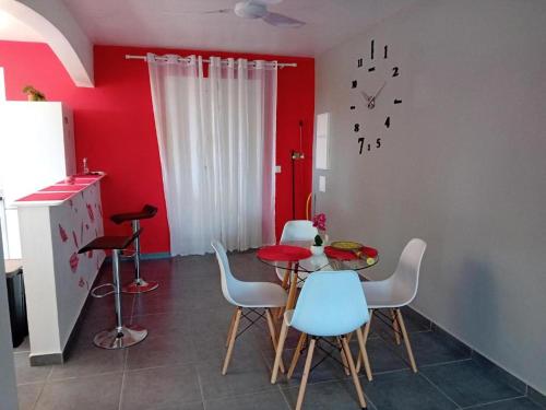 a kitchen with a table and chairs and a red wall at Studio La Félicité in Le Moule