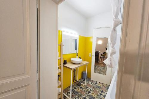 La salle de bains est pourvue d'un lavabo et d'un mur jaune. dans l'établissement Elegencia-T2 de charme-Hyper centre-Fibre, à Angers